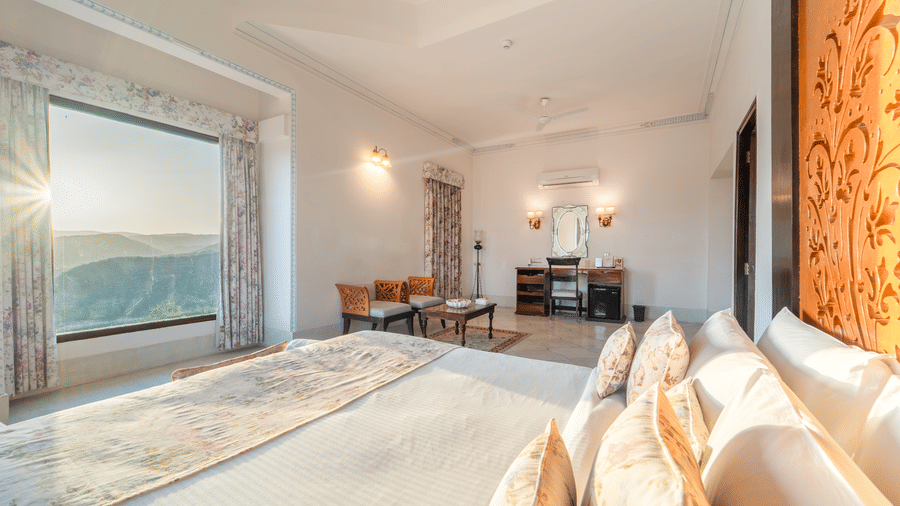 A warm, sunlit bedroom featuring heritage-style decor and plush floral-patterned pillows - Fateh Garh, Udaipur