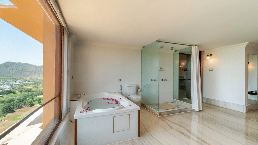 A modern wellness area within a suite featuring a private jacuzzi tub and a glass-enclosed shower - Fateh Garh, Udaipur