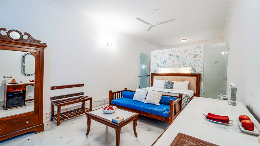 A vibrant suite interior featuring a bright blue wooden daybed, white marble floors, and heritage furniture - Fateh Garh, Udaipur