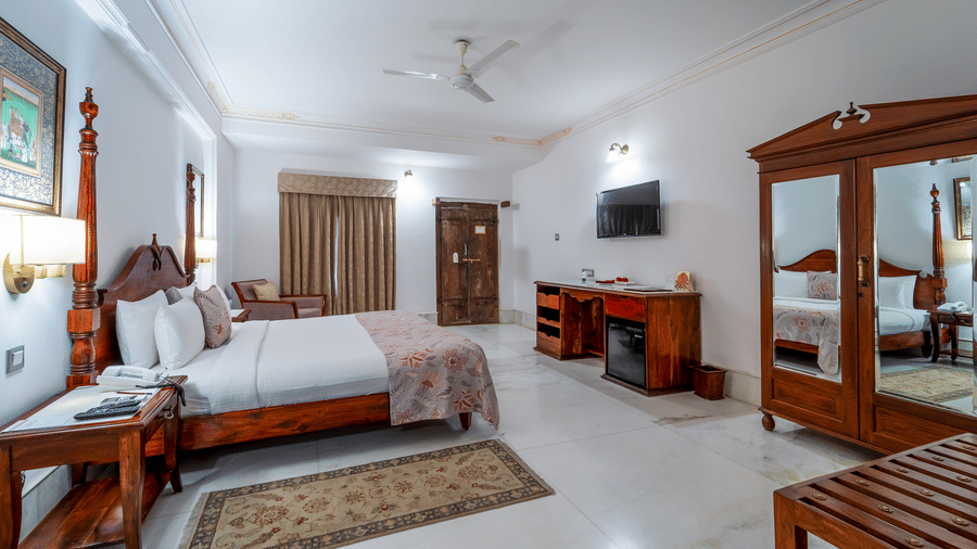 A regal bedroom interior showcasing a 2-poster bed, polished marble floors, and a traditional wooden armoire - Fateh Garh, Udaipur