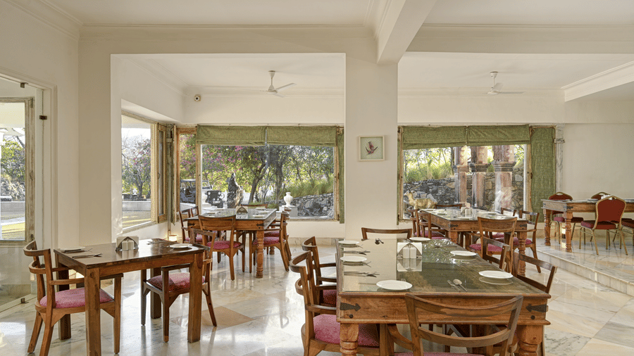 Lobby restaurant at Fateh Safari Resort, Kumbhalgarh featuring sets of tables and chairs and a view of outdoor.