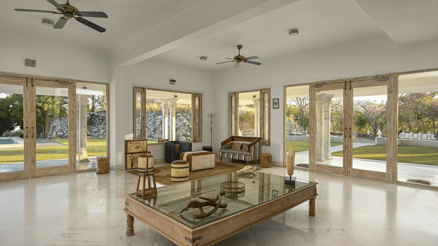 Reception lobby at Fateh Safari Resort, Kumbhalgarh featuring sofa sets, stools, centre table, a show piece at the centre of the room with antique and decorative items placed on it. 