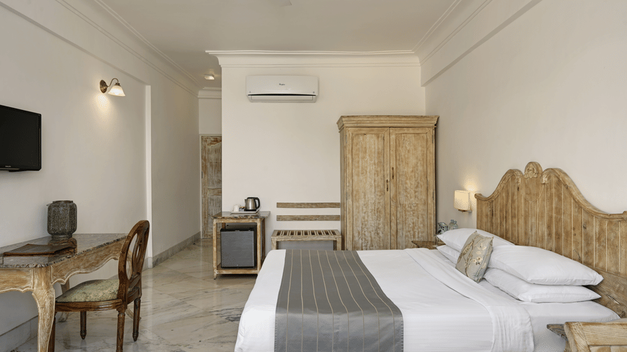 Superior Room with Balcony at Fateh Safari Resort, Kumbhalgarh featuring a double size bed, a flat TV screen, a work desk and chair, a cabinet table, a wardrobe, and an air-conditioner.