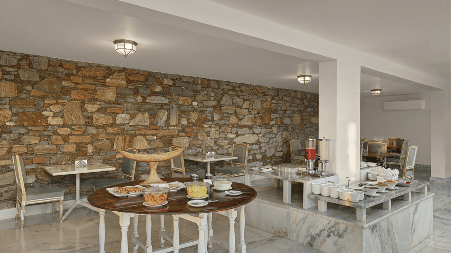 Restaurant at Fateh Safari Suites, Kumbhalgarh featuring dining tables and chairs and food counters.