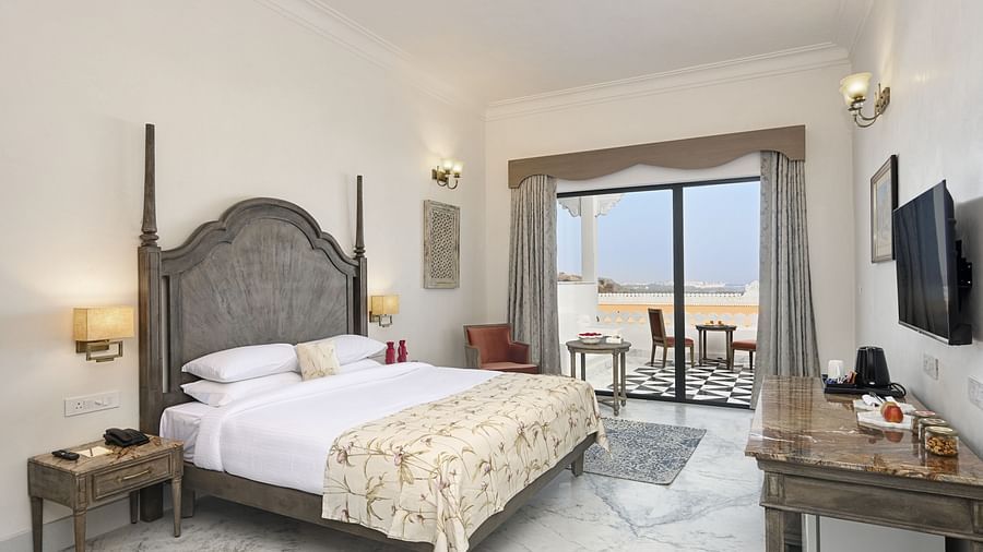 Fateh Vilas Udaipur - Interior view of the Renaissance Room with sit out featuring a king size bed white decor and a balcony