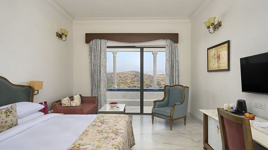 Fateh Vilas Udaipur - interior view of the Plunge Pool Suite featuring a bed a television a coffee table sofa and a balcony