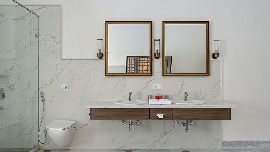 Fateh Vilas Udaipur - interior view of the bathroom featuring two mirrors two wash basins a shower area