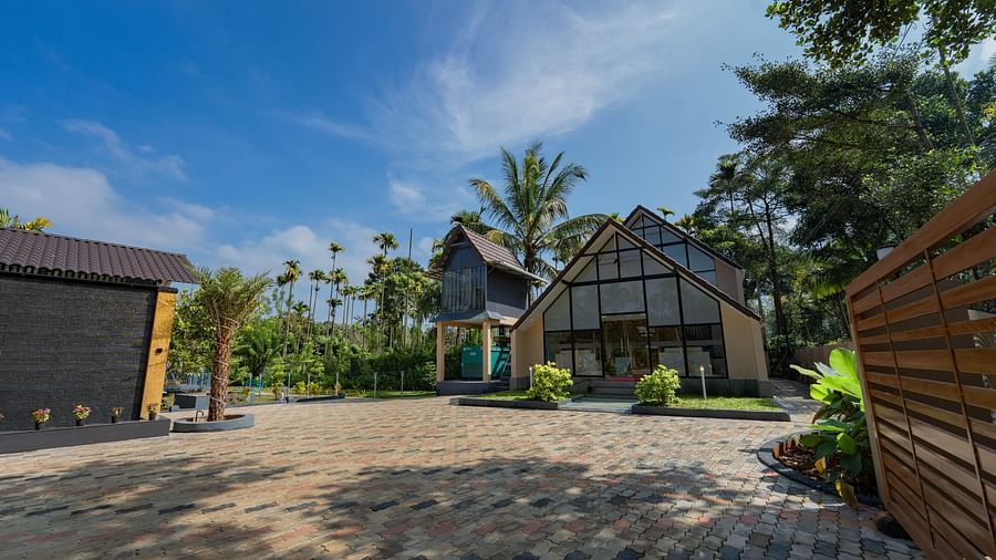 Building with a large open area in front of it with trees behind it at Feel Free Retreat, Wayanad