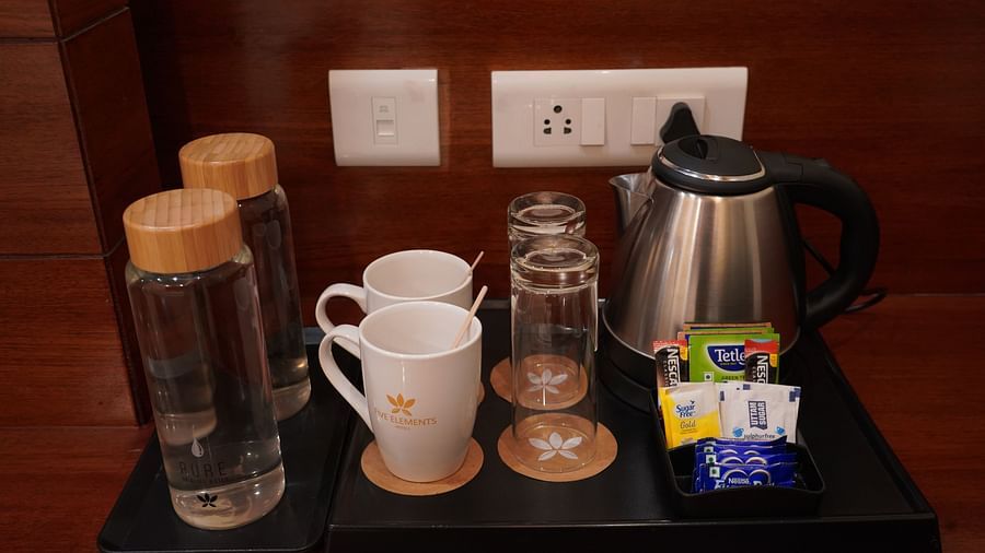 An image of a tray which has a tea and coffee maker, two bottles of water, two cups, two glasses, and some sachets of coffee and sugar - Five Elements Hotel, Jodhpur