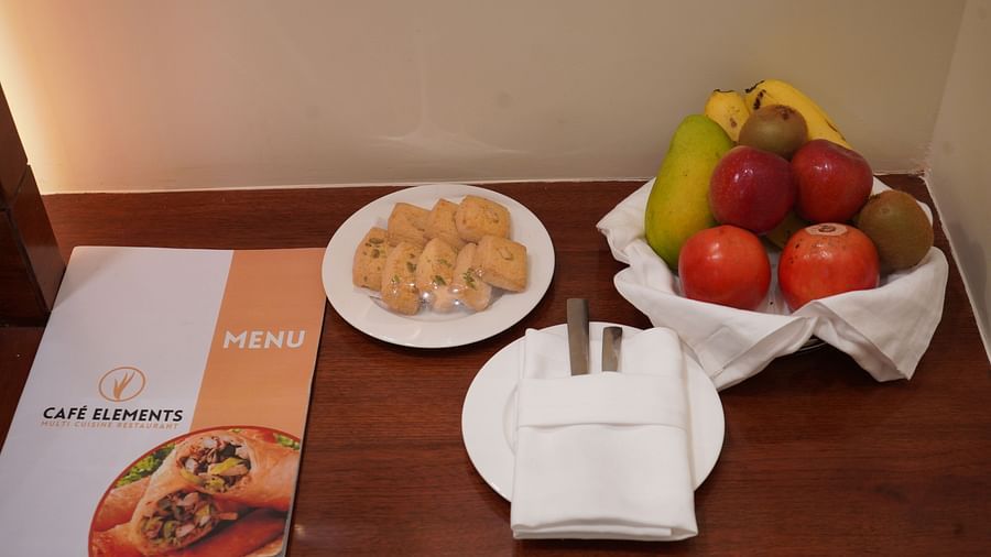 An image of a table where fruits and cookies are placed along with cutlery at Five Elements Hotel, Jodhpur