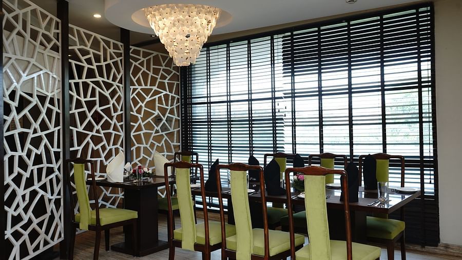 An image of a dining table with several chairs and a dinig atble in a restaurant - Five Elements Hotels North Avenue, Delhi