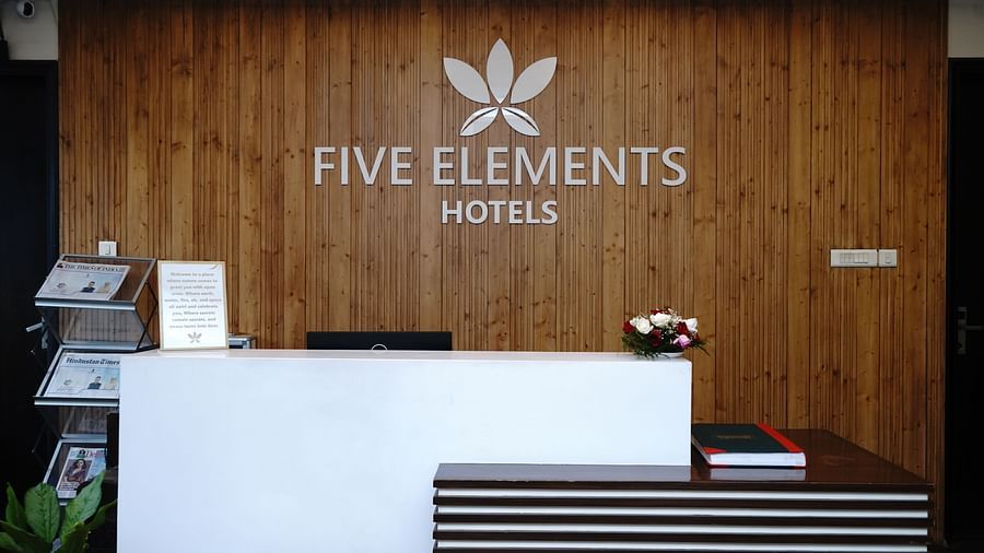 An image of a reception lobby featuring a desk featuring a welcome note, a flower bouquet, and a shack full of newspapers and magazines at Five Elements Hotels North Avenue, Delhi