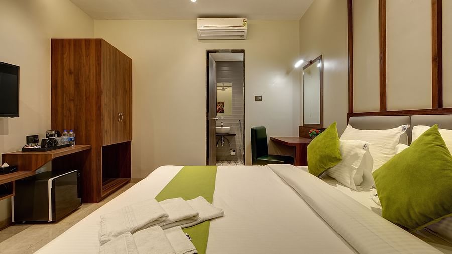 A double bed with a wardrobe diagonally opposite it inside Classic AC Room - Fortune House, Magarpatta