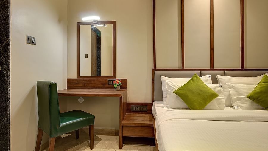 A double bed with a side table next to it inside Classic AC Room - Fortune House, Magarpatta