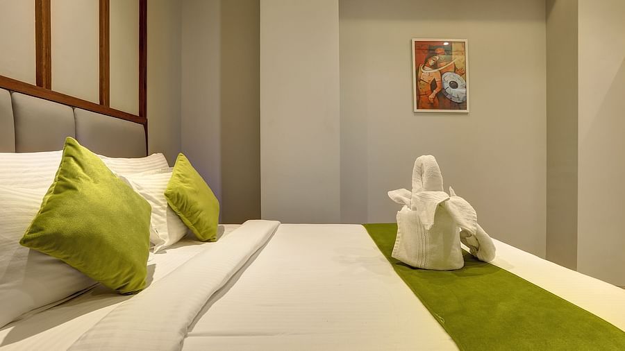 A close up shot of a double bed with dove towels on it inside Classic AC Room - Fortune House, Magarpatta