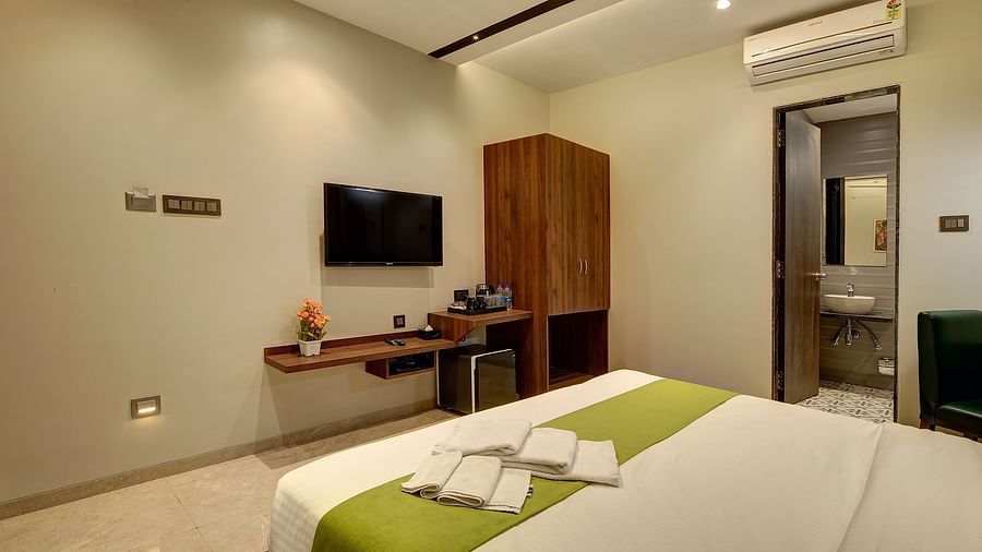 A double bed with a tv wall mounted opposite it inside Classic AC Room - Fortune House, Magarpatta