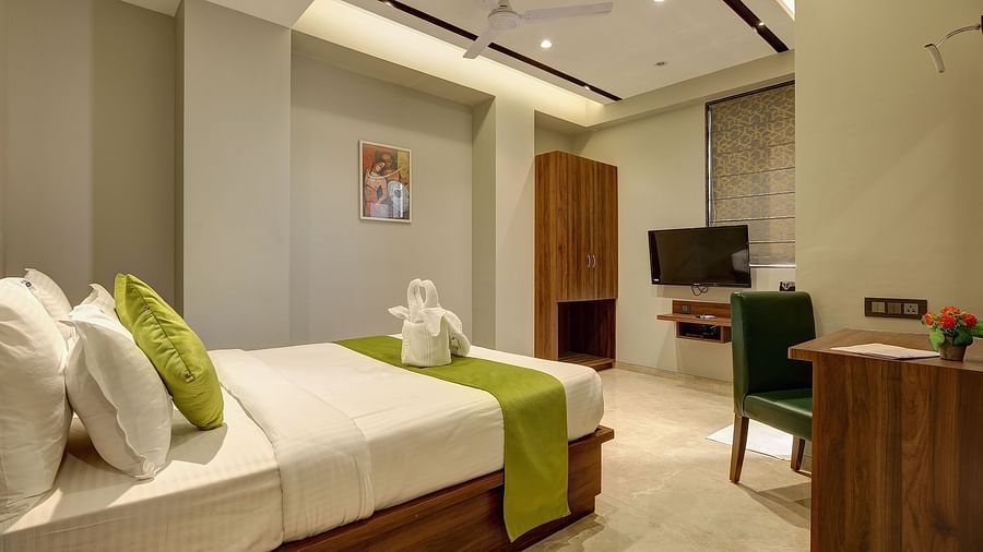 A double bed with a tv opposite it inside Classic AC Room - Fortune House, Magarpatta