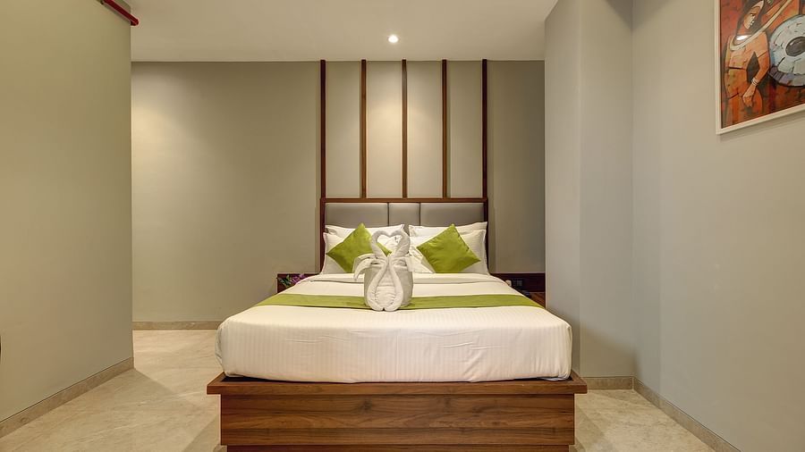 A a double bed with green runner on it inside Classic AC Room - Fortune House, Magarpatta