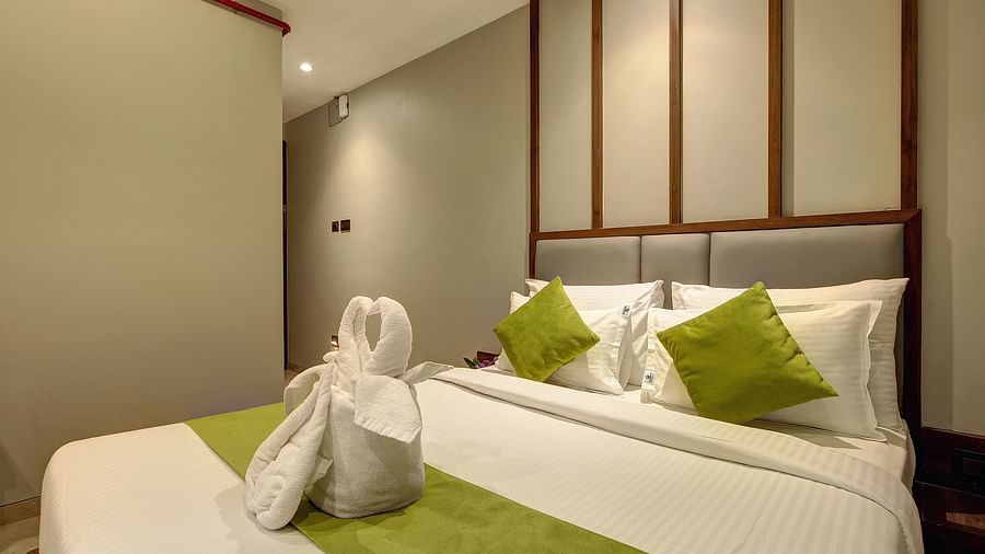 A double bed with dove towels on top of it inside Classic AC Room - Fortune House, Magarpatta