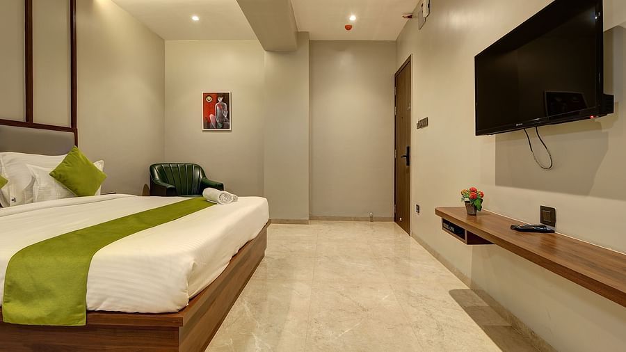 A double bed with a tv wall mounted opposite it inside Luxury Suite - Fortune House, Magarpatta