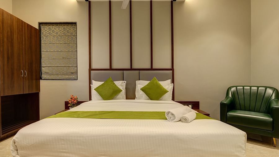 Double bed with a chair next to it inside Luxury Suite - Fortune House, Magarpatta