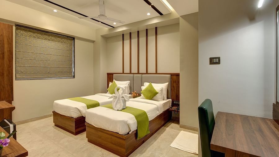 Twin beds inside Premium Twin Sharing Room with a study table next to it - Fortune House, Magarpatta