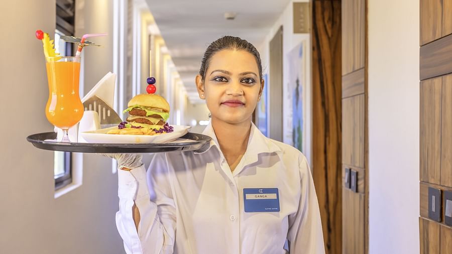 Hotel staff carrying a tray with burger and cocktail in corridor - Golden Tulip, Candolim, Goa
