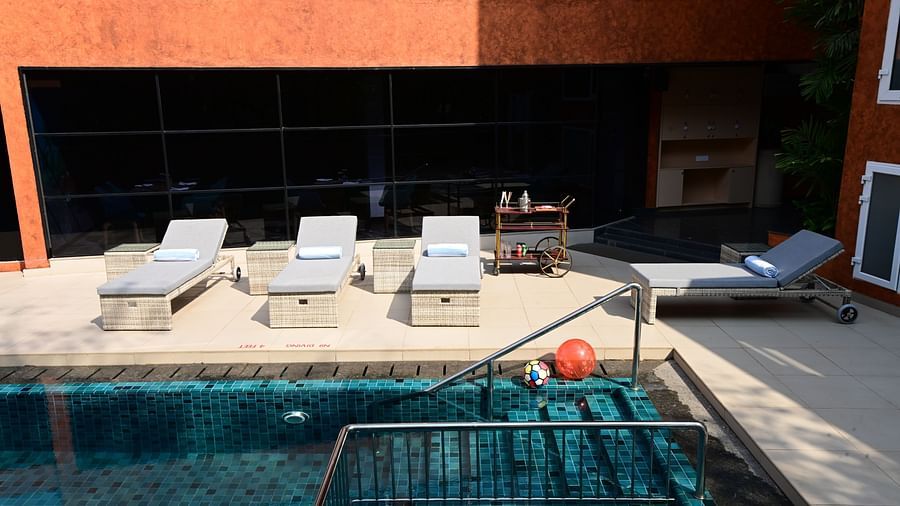 The outdoor swimming pool area with lounging chairs placed besides it at Golden Tulip Vagator, Goa