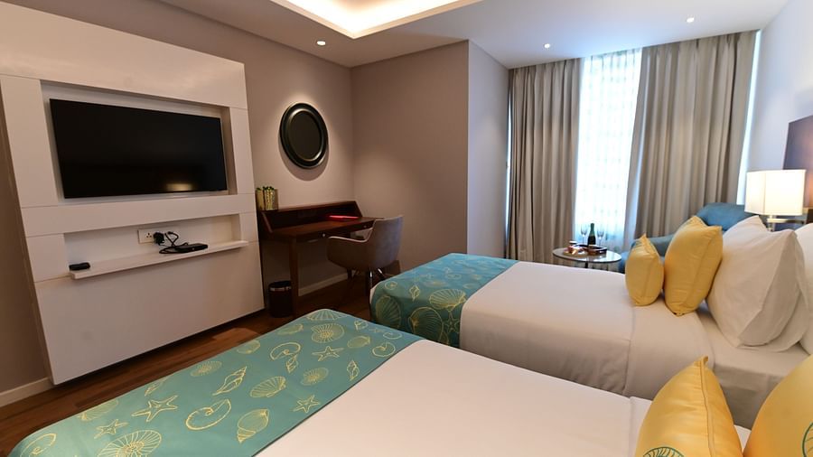 A room at Golden Tulip Vagator, Goa with twin beds, a television and a work desk and chair set up