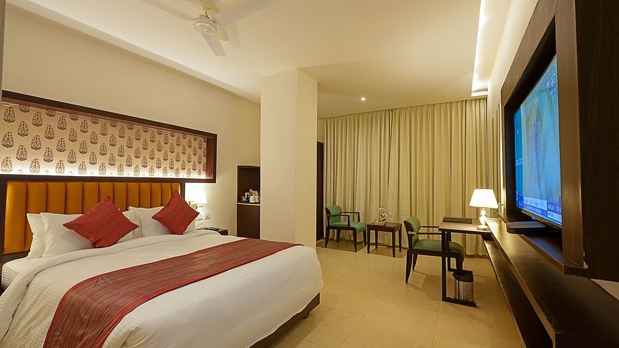 Deluxe room with a television and a king size bed at Grand Continent, Secunderabad