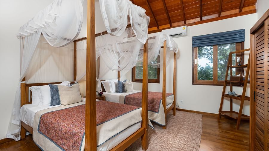 A bright and airy bedroom featuring a wooden canopy bed with white drapes and a view of the greenery outside - Executive Suite at Heavensa Villas and Suites by the Clarks, Galle