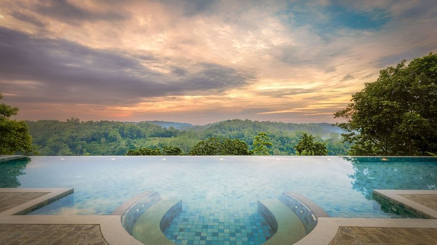 A stunning infinity pool with a panoramic view of the hills, set against a dramatic sunset sky - Heavensa Villas and Suites by the Clarks, Galle
