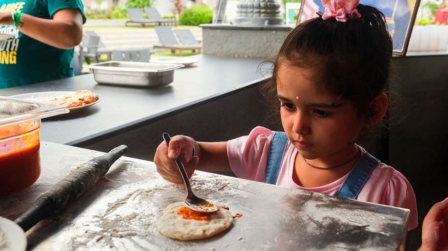 a little girl making a pizza