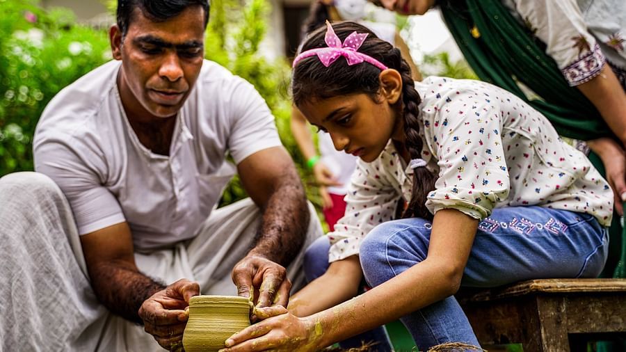a ceramist teaching a little girl pottery