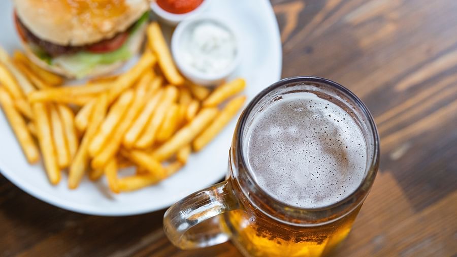 a glass of beer with a plate of fries, burger and dips
