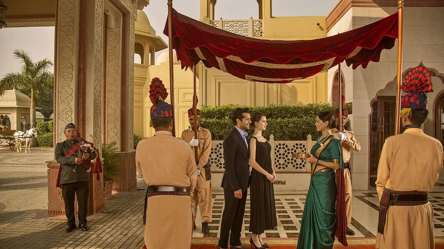 Guests are greeted under a canopy with ceremonial guards and a bagpipe player at a grand hotel entrance - Heritage Village Resorts & Spa, Manesar