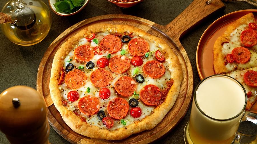 a table with a large pizza and a mug of beer kept next to it - Heritage Village Resorts & Spa, Manesar
