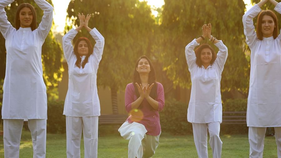 An image of five woman doing yoga in an open lawn