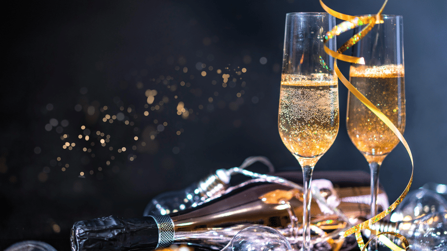 2 flutes of sparkling champagne sit amidst festive tinsel and bubbles | New years eve Gurgaon