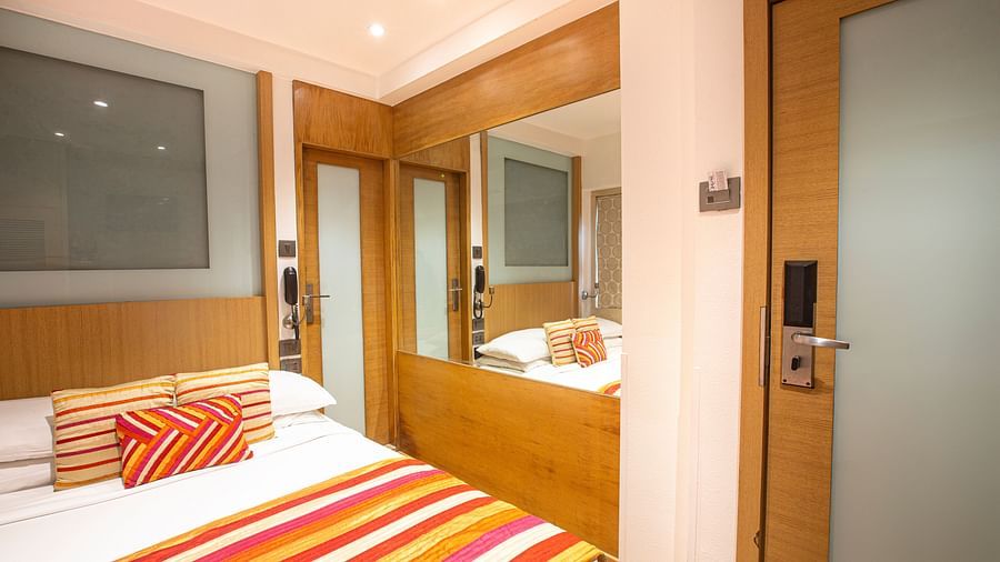 A side angle view of an economy room featuring a comfy bed and a dressing table, highlighting a cozy and inviting atmosphere.