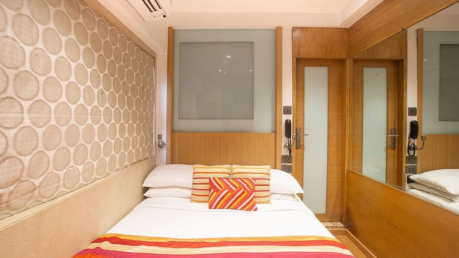 A front view of an economy room showcasing a comfy bed adorned with pillows and a blanket, creating a welcoming and cozy atmosphere.