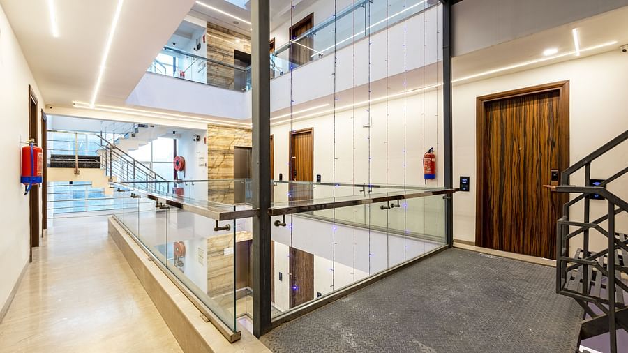 Modern hotel corridor with glass railings, bright lighting, and sleek interiors at Hotel Bawa, Gurgaon.