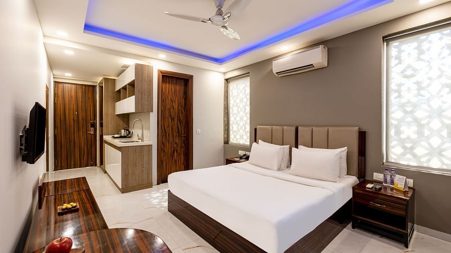 Spacious king size bed in a room with soft lighting and stylish wooden furniture at Hotel Bawa, Gurgaon.