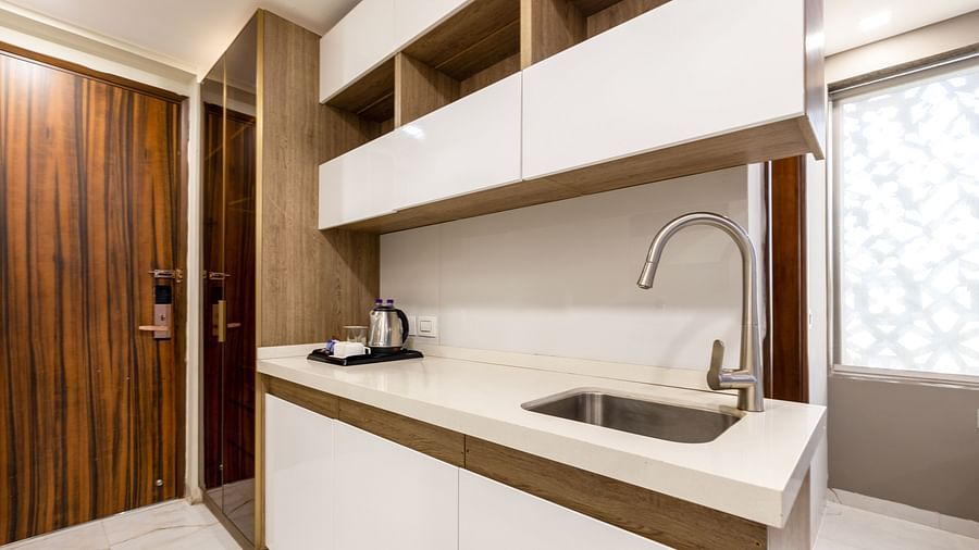 Modern kitchenette with sleek cabinets, a sink, and ample storage at Hotel Bawa, Gurgaon.