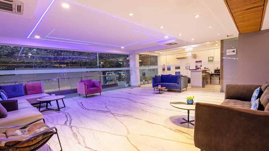 Lounge space with modern furniture and vibrant purple ceiling lights at Hotel Bawa, Gurgaon.
