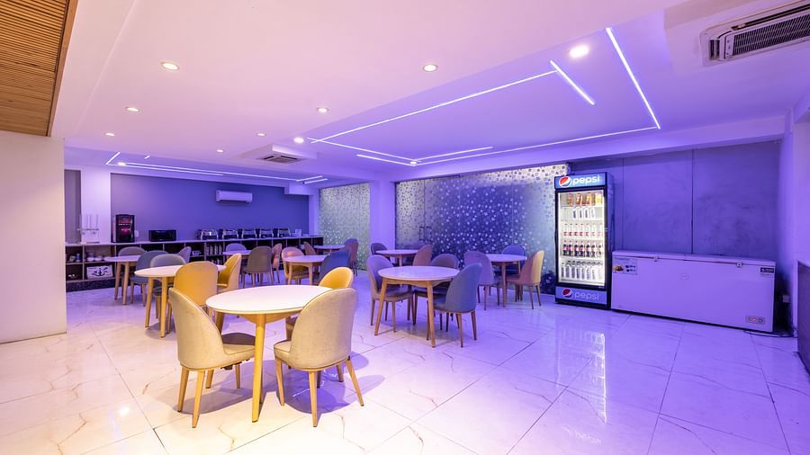 Chairs and tables in a spacious restaurant with soft LED lighting at Hotel Bawa, Gurgaon.