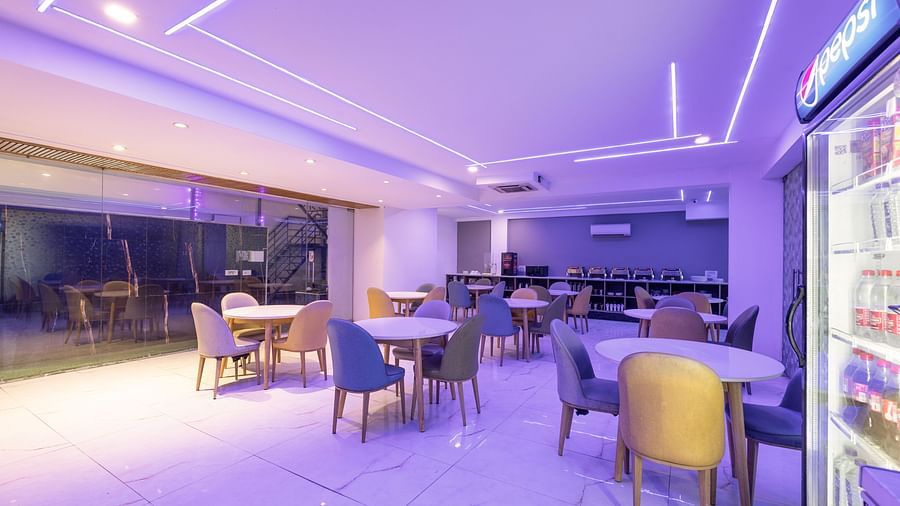 An LED-lit restaurant with chairs and tables at Hotel Bawa, Gurgaon.