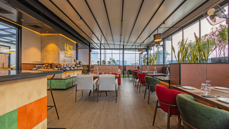 Dining floor at Koi Garden restaurant. Tables and seating options are arranged across the room. A buffet counter stands on the left side under ceiling panels.