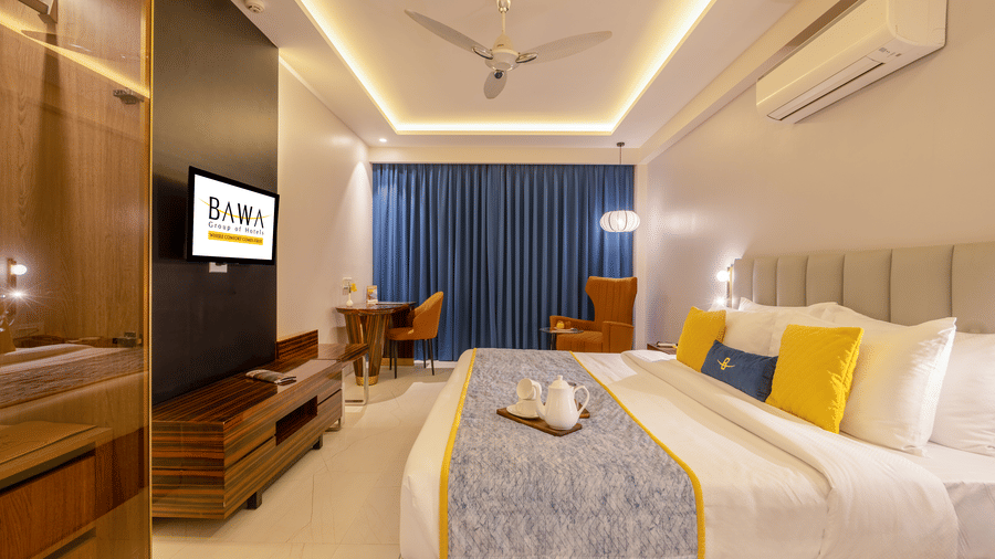 Premium hotel room interior with a king-sized bed, yellow accent pillows, and flat-screen TV.