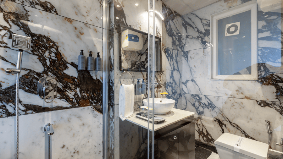 Premium bathroom with marble walls, a glass walk-in shower, and a white vanity sink.